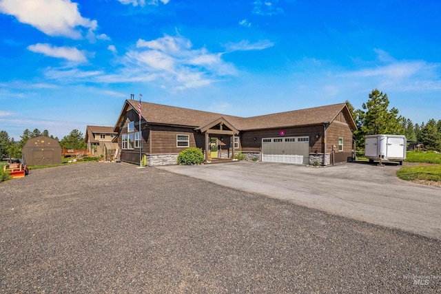 656 Fox Ridge Ln, Mccall, ID 83638 - view of front of home with a storage shed, a garage, asphalt driveway, and stone siding