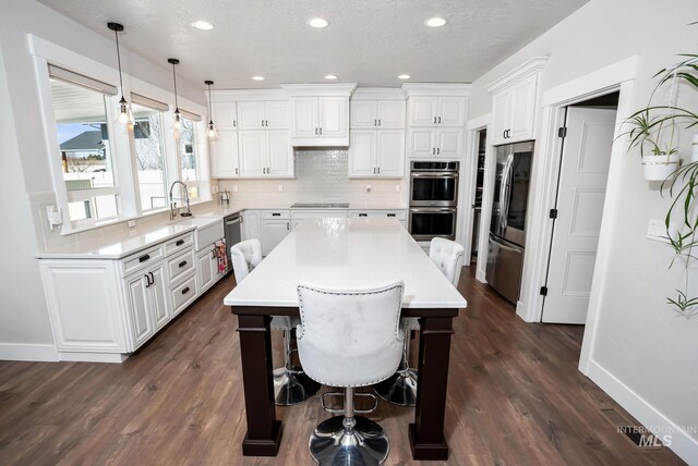 7063 S Pear Blossom, Meridian, ID 83642 - kitchen featuring appliances with stainless steel finishes, backsplash, white cabinets, dark wood-type flooring, and light countertops