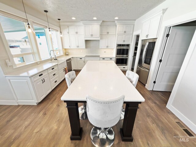 7063 S Pear Blossom, Meridian, ID 83642 - kitchen with stainless steel appliances, recessed lighting, a kitchen island, a textured ceiling, and tasteful backsplash