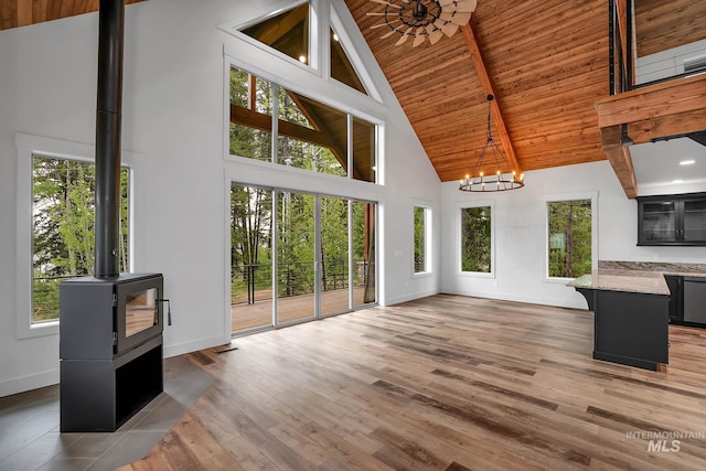 1 Caribou Pkwy, Cascade, ID 83611 - unfurnished living room with high vaulted ceiling, a chandelier, baseboards, a wood stove, and plenty of natural light