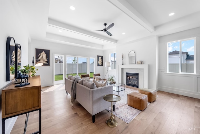 living room featuring ceiling fan, beam ceiling, light hardwood / wood-style floors, and a healthy amount of sunlight