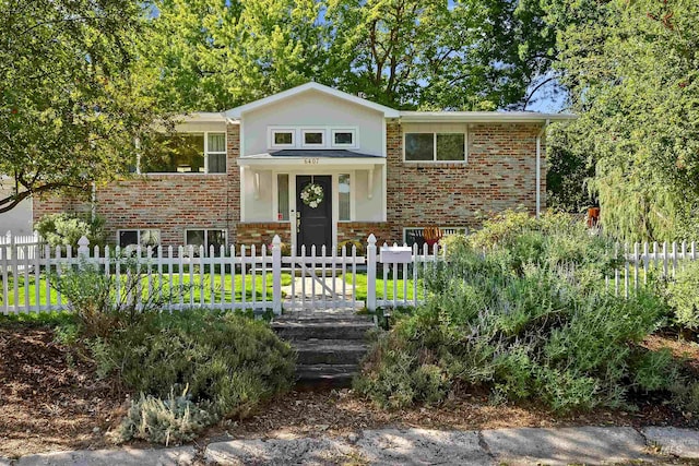 split foyer home featuring brick siding and a fenced front yard