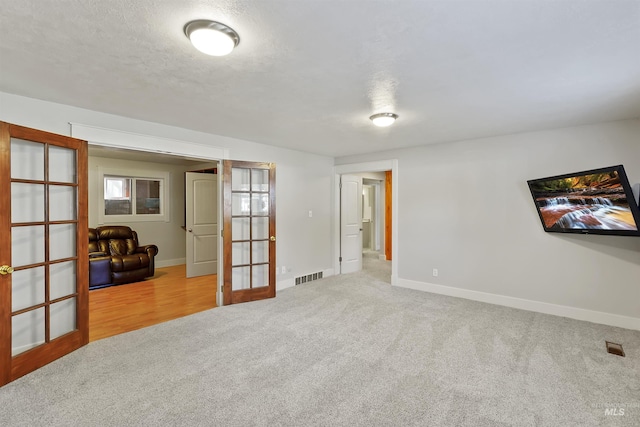 empty room featuring carpet flooring, french doors, visible vents, and baseboards