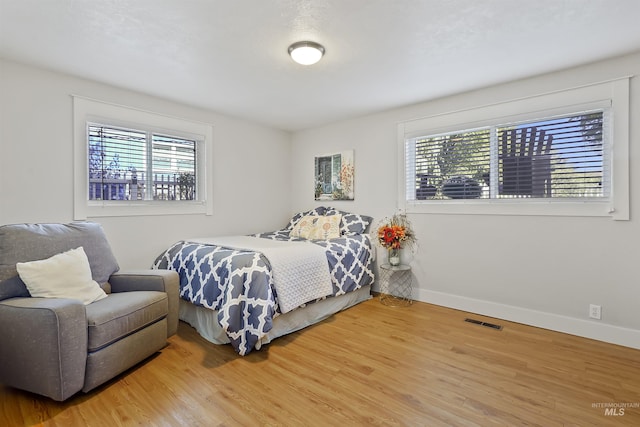 bedroom featuring visible vents, baseboards, and wood finished floors