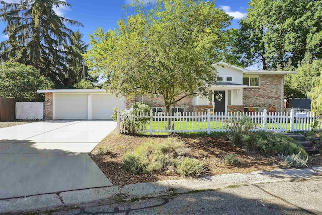 view of front of home featuring concrete driveway, a garage, brick siding, and a fenced front yard