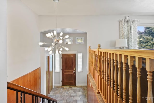 foyer entrance featuring a notable chandelier, arched walkways, baseboards, and stone finish flooring