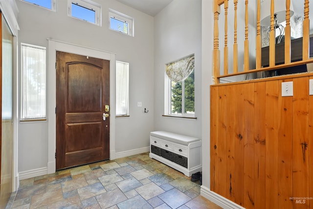 entrance foyer with baseboards, a wealth of natural light, and stone finish flooring