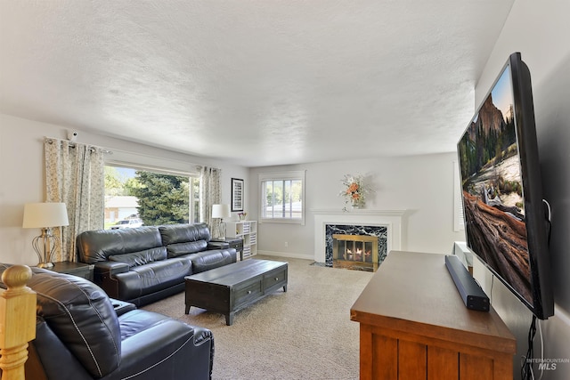 living area with light carpet, a textured ceiling, baseboards, and a high end fireplace