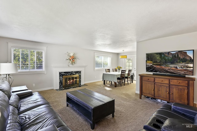 carpeted living area with a high end fireplace and baseboards