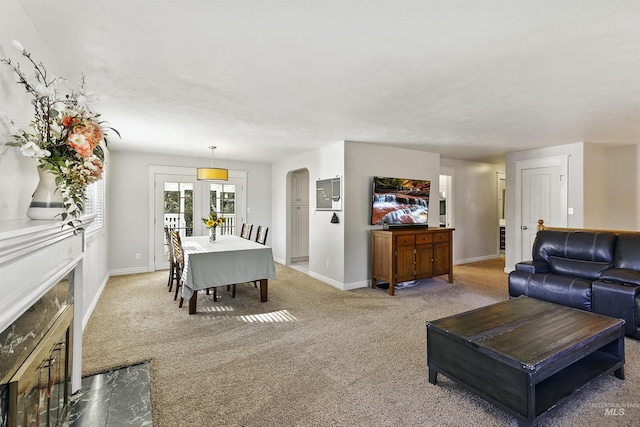 living room with a premium fireplace, arched walkways, light colored carpet, and baseboards