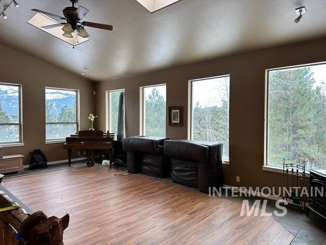 interior space with lofted ceiling, rail lighting, ceiling fan, and wood-type flooring