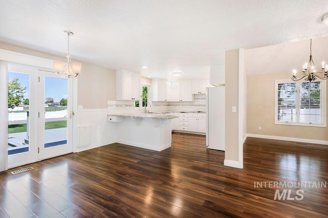 2500 W Orchard Ave, Nampa, ID 83651 - kitchen with freestanding refrigerator, a peninsula, an inviting chandelier, and visible vents