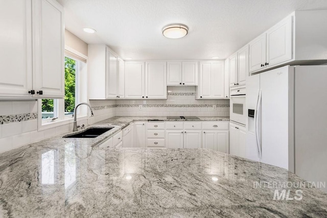 2500 W Orchard Ave, Nampa, ID 83651 - kitchen with decorative backsplash, white appliances, light stone countertops, white cabinets, and a sink