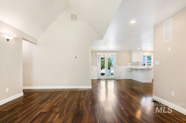 2500 W Orchard Ave, Nampa, ID 83651 - unfurnished living room featuring baseboards, visible vents, lofted ceiling, and dark wood-type flooring