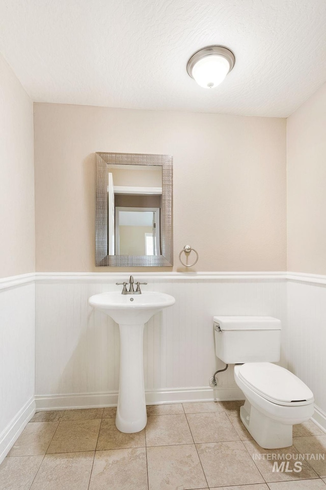 2500 W Orchard Ave, Nampa, ID 83651 - bathroom featuring toilet, tile patterned flooring, and a wainscoted wall
