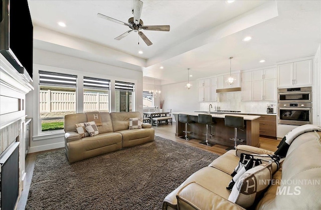 4603 S Hennessy Ave, Meridian, ID 83642 - living area with light wood-type flooring, a ceiling fan, recessed lighting, a chandelier, and a tray ceiling