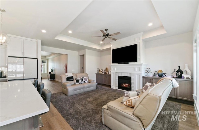 4603 S Hennessy Ave, Meridian, ID 83642 - living room with a raised ceiling, a ceiling fan, wood finished floors, recessed lighting, and a lit fireplace