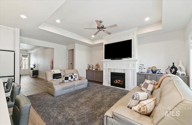4603 S Hennessy Ave, Meridian, ID 83642 - living room featuring a ceiling fan, wood finished floors, recessed lighting, a glass covered fireplace, and a tray ceiling