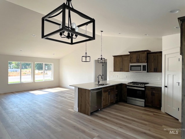 kitchen with kitchen peninsula, appliances with stainless steel finishes, light wood-type flooring, sink, and lofted ceiling