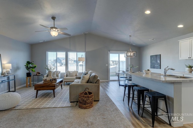 living room featuring lofted ceiling, light hardwood / wood-style floors, sink, and a wealth of natural light