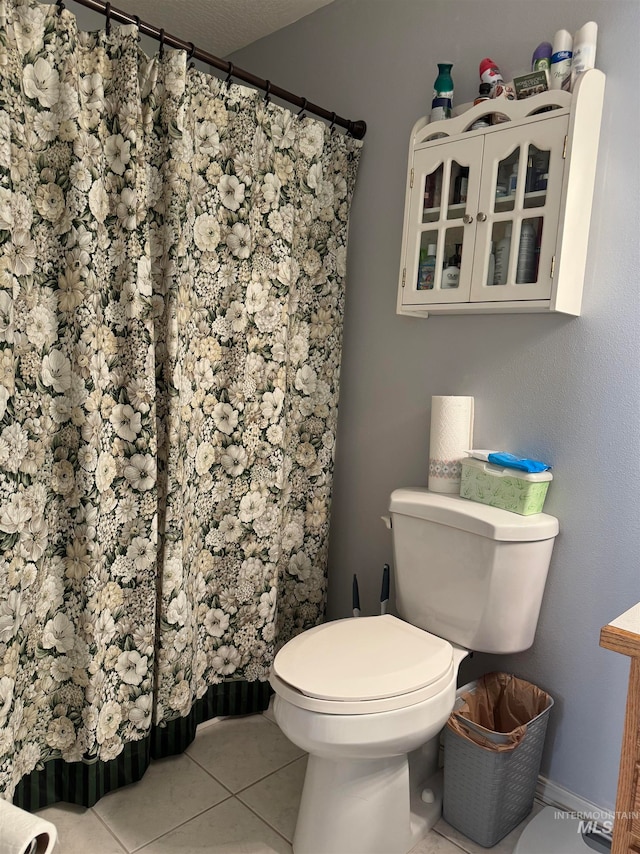 bathroom with a shower with shower curtain, toilet, and tile patterned floors