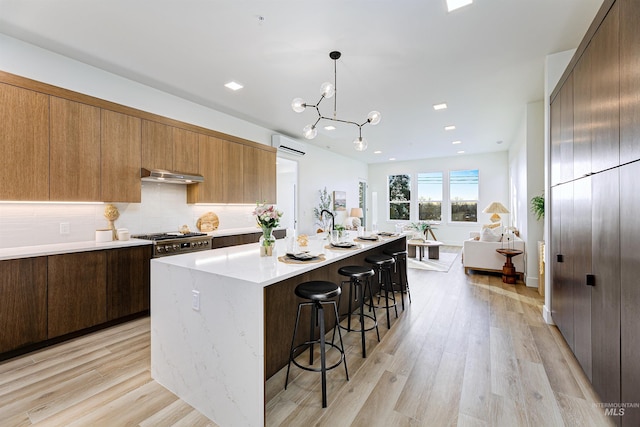 55 E State St Unit 303, Eagle, ID 83616 - kitchen featuring an AC wall unit, pendant lighting, light hardwood / wood-style floors, a breakfast bar, and a center island with sink