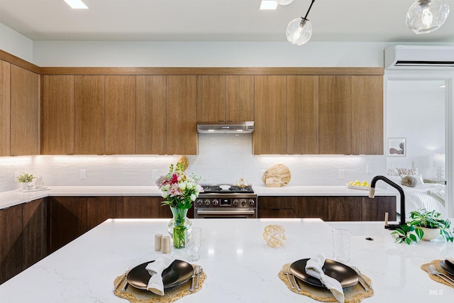55 E State St Unit 303, Eagle, ID 83616 - kitchen featuring high end stainless steel range oven, hanging light fixtures, a wall mounted AC, and tasteful backsplash