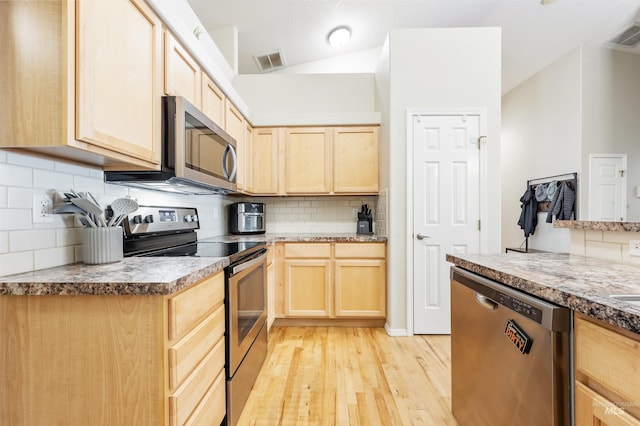 3189 S Kramer Ln, Boise, ID 83706 - kitchen with light brown cabinetry, appliances with stainless steel finishes, decorative backsplash, light wood-type flooring, and vaulted ceiling