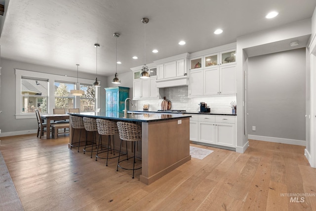 1315 N Luge Ave, Eagle, ID 83616 - kitchen with baseboards, light wood-style floors, an island with sink, a breakfast bar, and recessed lighting