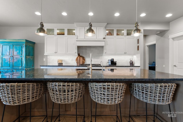1315 N Luge Ave, Eagle, ID 83616 - kitchen with tasteful backsplash, a large island with sink, dark stone countertops, white cabinets, and recessed lighting