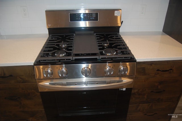 details with stainless steel range with gas stovetop, dark brown cabinets, and backsplash