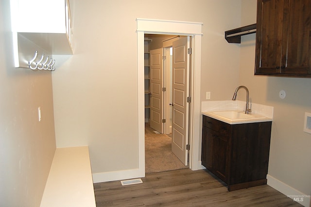 kitchen with dark wood-type flooring, dark brown cabinetry, and sink