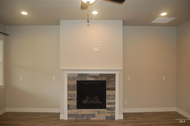 unfurnished living room featuring a stone fireplace, wood-type flooring, and ceiling fan