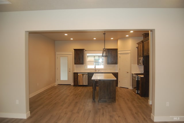 kitchen featuring dark hardwood / wood-style floors, stainless steel appliances, sink, pendant lighting, and a center island