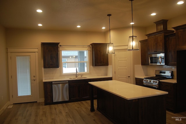 kitchen with sink, a center island, hanging light fixtures, stainless steel appliances, and dark wood-type flooring