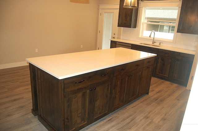 kitchen with dark brown cabinetry, sink, a kitchen island, and dark hardwood / wood-style flooring