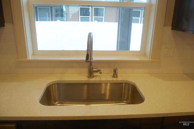 details with sink, light stone countertops, and tasteful backsplash