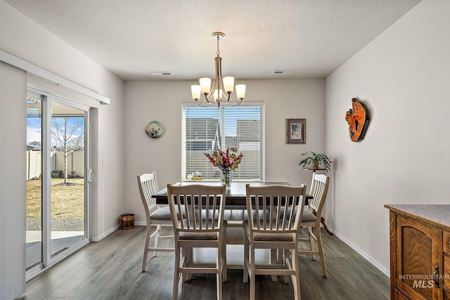 dining space with baseboards, wood finished floors, and an inviting chandelier