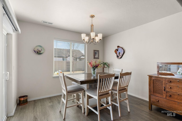 dining area featuring an inviting chandelier, visible vents, baseboards, and wood finished floors