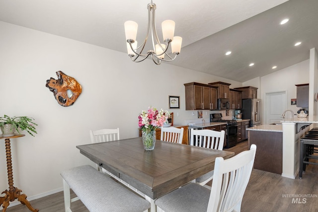 dining room with lofted ceiling, recessed lighting, an inviting chandelier, wood finished floors, and baseboards