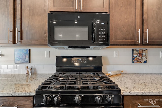 kitchen featuring black appliances, light stone counters, and decorative backsplash