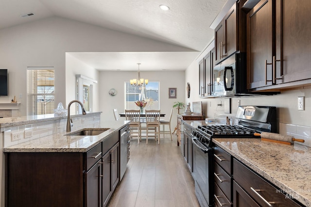 kitchen featuring visible vents, gas stove, a sink, dark brown cabinets, and black microwave