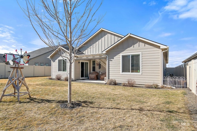 rear view of property featuring a yard, board and batten siding, a patio area, and a fenced backyard