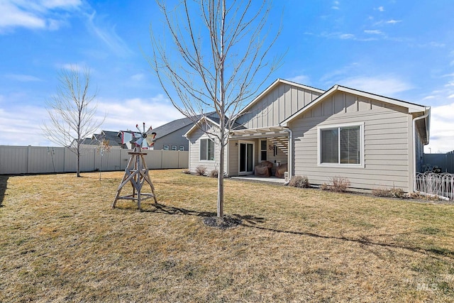 rear view of house with a patio, board and batten siding, a fenced backyard, and a lawn