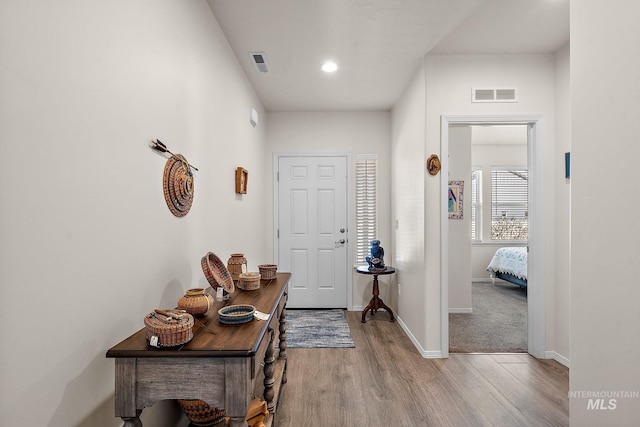 foyer entrance featuring wood finished floors, visible vents, and baseboards