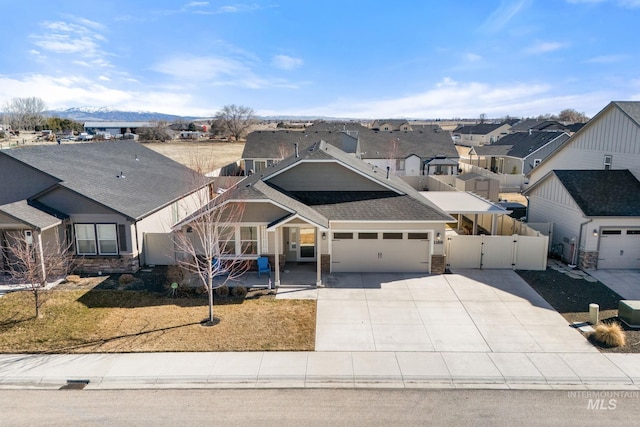 view of front facade featuring a garage, driveway, a residential view, a gate, and fence