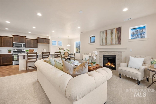 living room featuring a tile fireplace and light hardwood / wood-style flooring