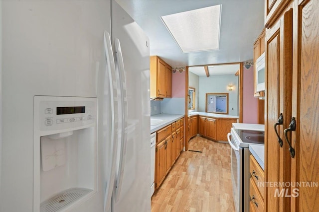 kitchen featuring white appliances, light wood finished floors, light countertops, and brown cabinetry