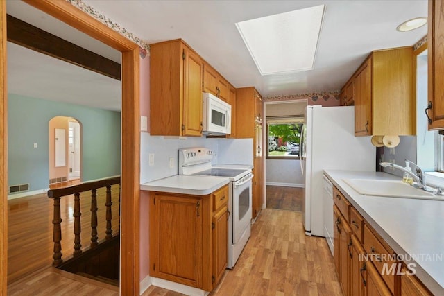 kitchen featuring white appliances, a sink, and light wood-style flooring