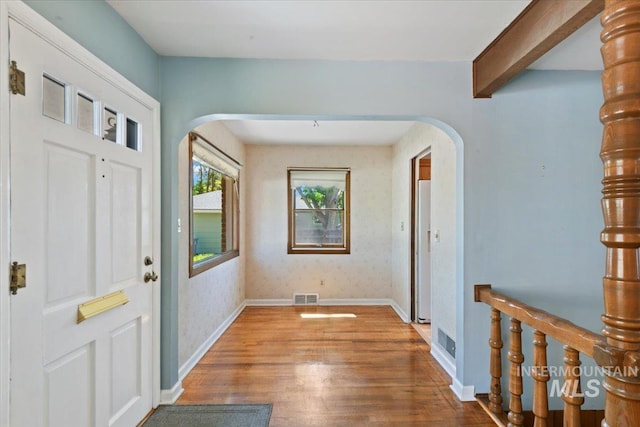 entryway featuring arched walkways, wood finished floors, and baseboards